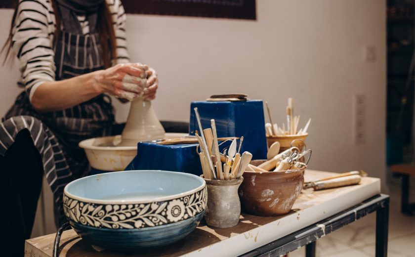 Woman hands working on pottery wheel and making a pot.